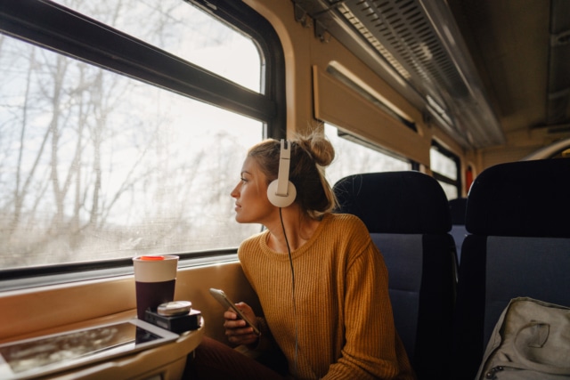 woman riding a train looking out of the window wearing headphones